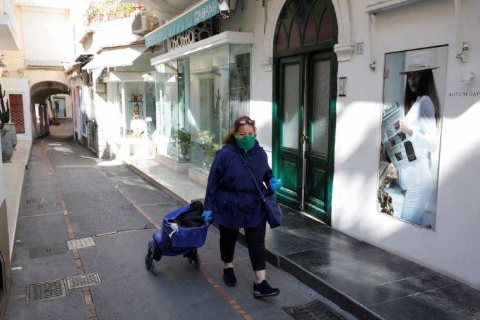 A woman wearing a protective face mask and gloves is seen in Capri, as the spread of coronavirus disease (COVID-19) continues in Capri, Italy, April 24, 2020. REUTERS/Ciro De Luca