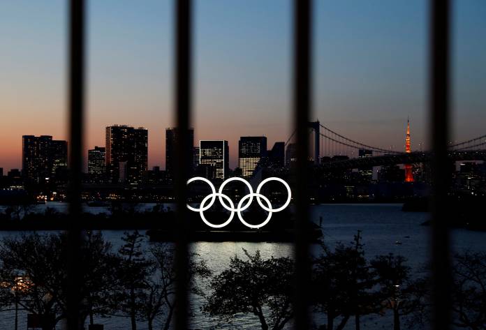 FILE PHOTO: The Olympic rings are pictured at dusk through a steel fence, at the waterfront area of the Odaiba Marine Park, after the postponing of the Olympic Games Tokyo 2020, due to the outbreak of coronavirus disease (COVID 19), in Tokyo
