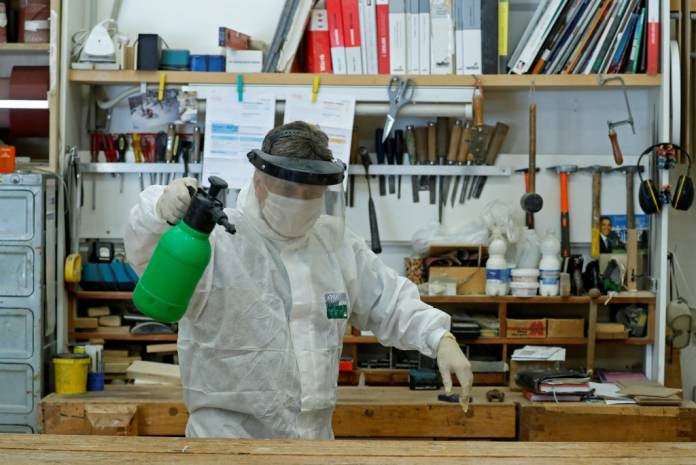 A carpenter wearing protective gear sanitises his carpentry, as the spread of coronavirus disease (COVID-19) continues, in Rome, Italy, April 27, 2020. REUTERS/Remo Casilli