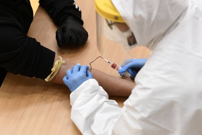 FILE PHOTO: Medical workers take blood samples for the coronavirus disease (COVID-19) tests at a converted gym in Cisliano, near Milan