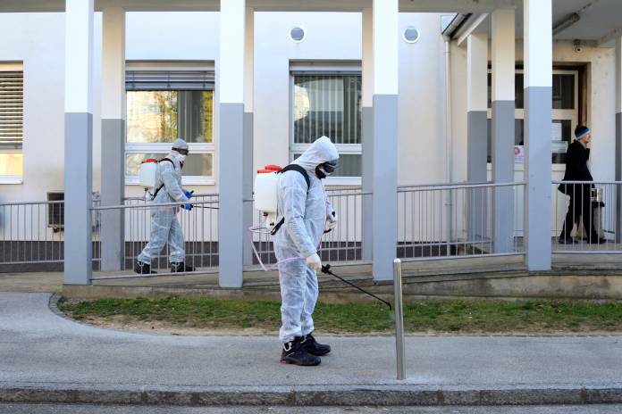 FILE PHOTO: A worker sprays disinfectant to prevent the spread of coronavirus disease (COVID-19), outside the hospital in Kranj