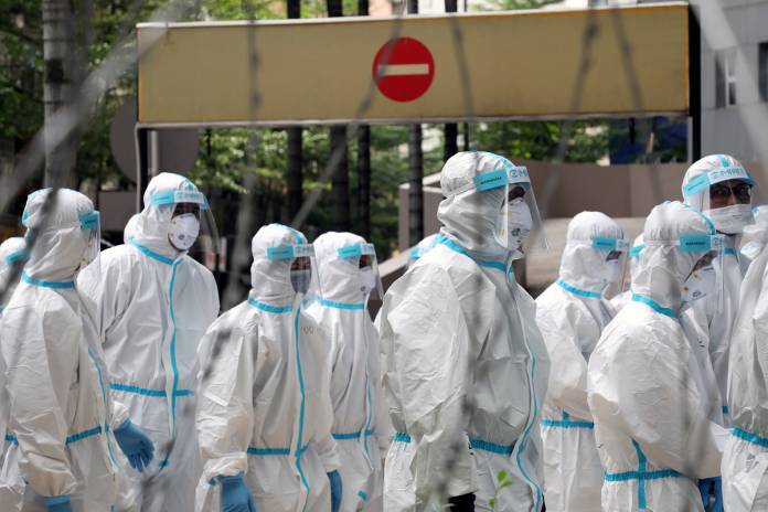 FILE PHOTO: Police officers wearing protective suits gather outside an apartment under enhanced lockdown to pick up illegal immigrants, during the movement control order due to the outbreak of the coronavirus disease (COVID-19), in Kuala Lumpur