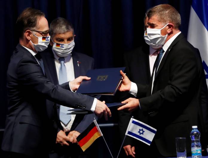 German Foreign Minister Heiko Maas and his Israeli counterpart Gabi Ashkenazi hand each other documents during their news conference in Jerusalem