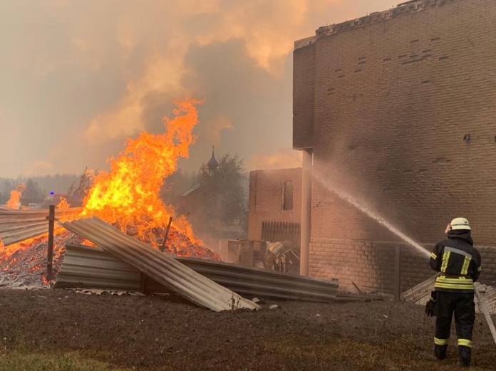 A firefighter tries to extinguish a fire burning in a village in Luhansk Region