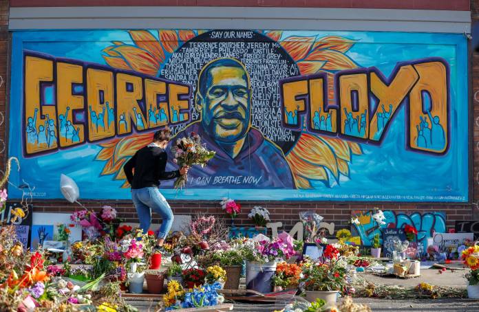 A woman holds a bouquet at the site of the arrest of George Floyd, in Minneapolis