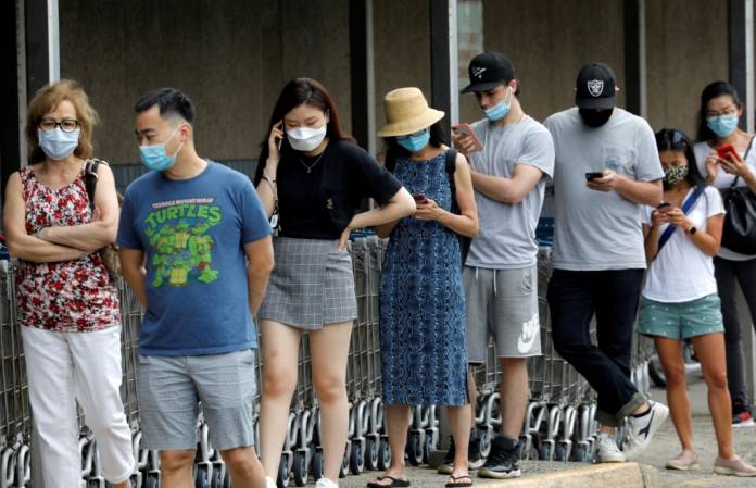 FILE PHOTO: People wear protective face masks outside at a shopping plaza after New Jersey Governor Phil Murphy said he would sign an executive order requiring people to wear face coverings outdoors to prevent a resurgence of the coronavirus disease (COVID-19), in Edgewater, New Jersey, U.S., July 8, 2020. REUTERS/Mike Segar