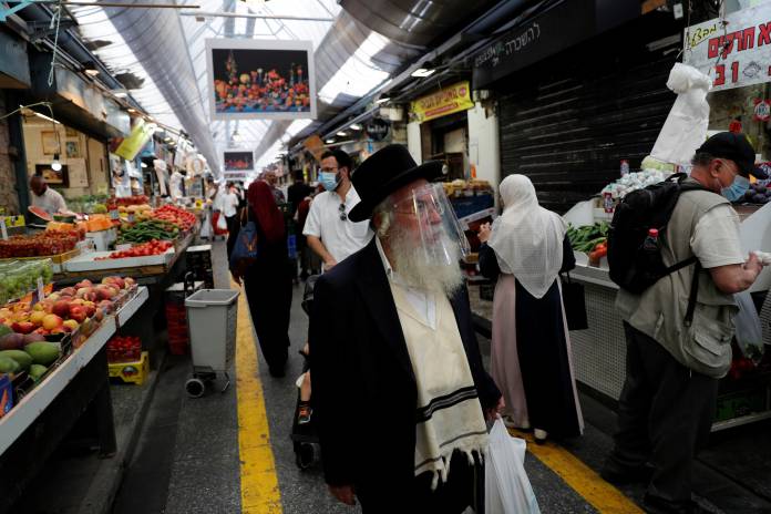 People wear face mask sas they shop in a main market in Jerusalem