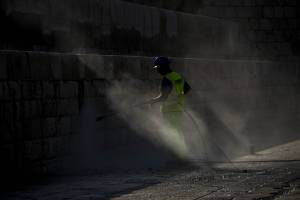 man-sprays-water-on-wall-in-breakwater-valletta