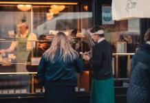 Denmark lifts all Covid measures A popular bakery serving customers with corona / covid-19 restrictions. The waitress is taking the order with a mask/face shield while an employee inside is preparing an order.